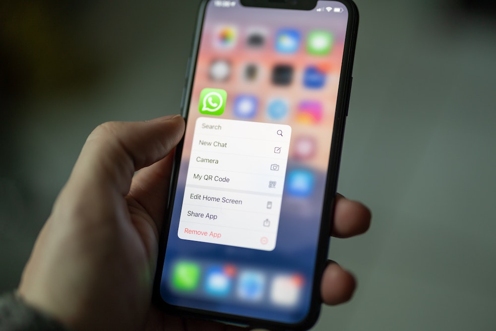 Hand holding a phone with whatsapp options, including remove whatsapp