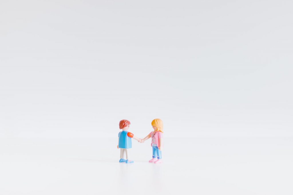Two figurines shaking hands on white background