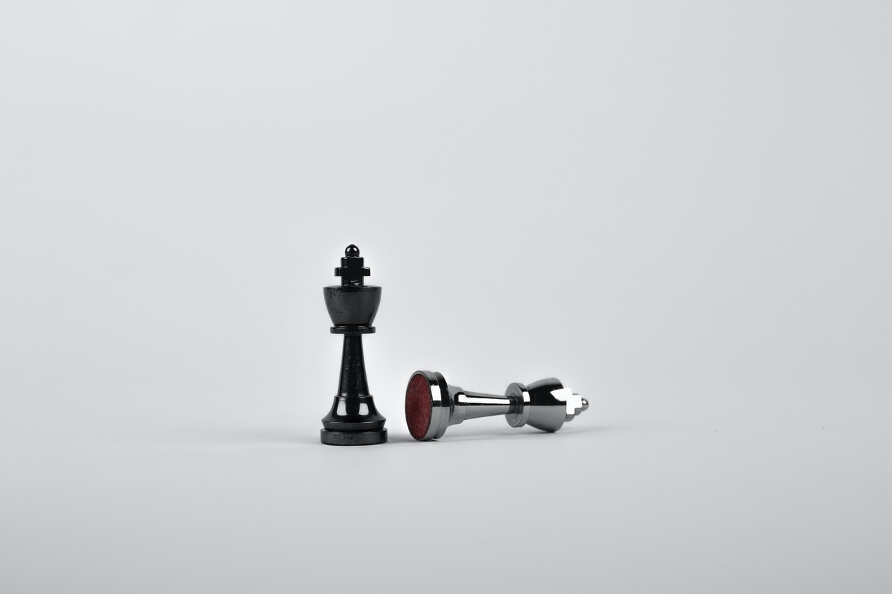 Two chess pieces against a white background, one knocked over
