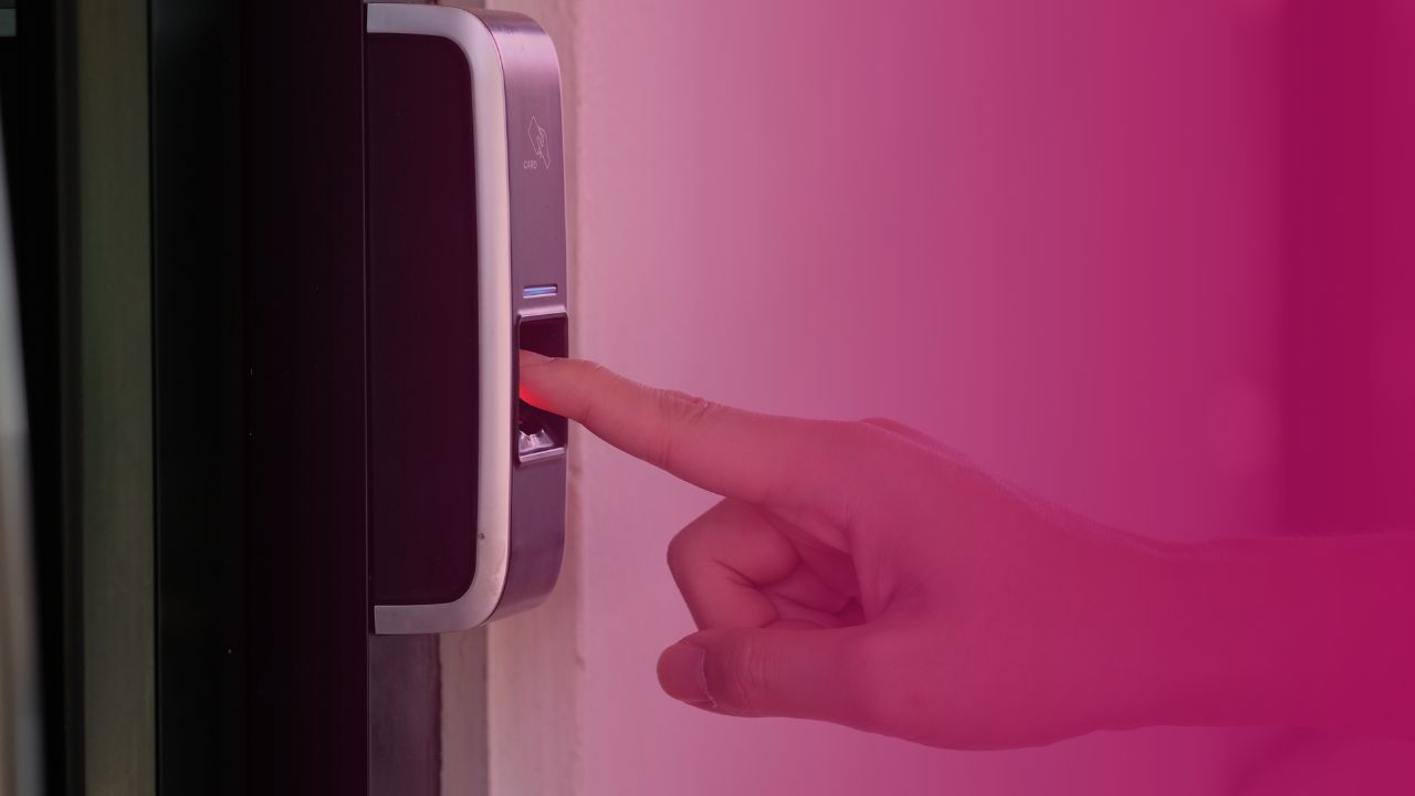 Person putting their finger on a biometric scanner in their workplace with the pink privacy 108 branded overlay