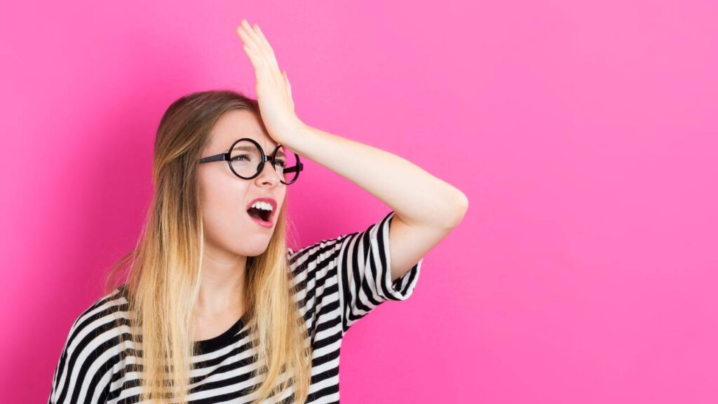 Blonde woman wearing a striped shirt touching her palm to her forehead (facepalm) indicating a mistake